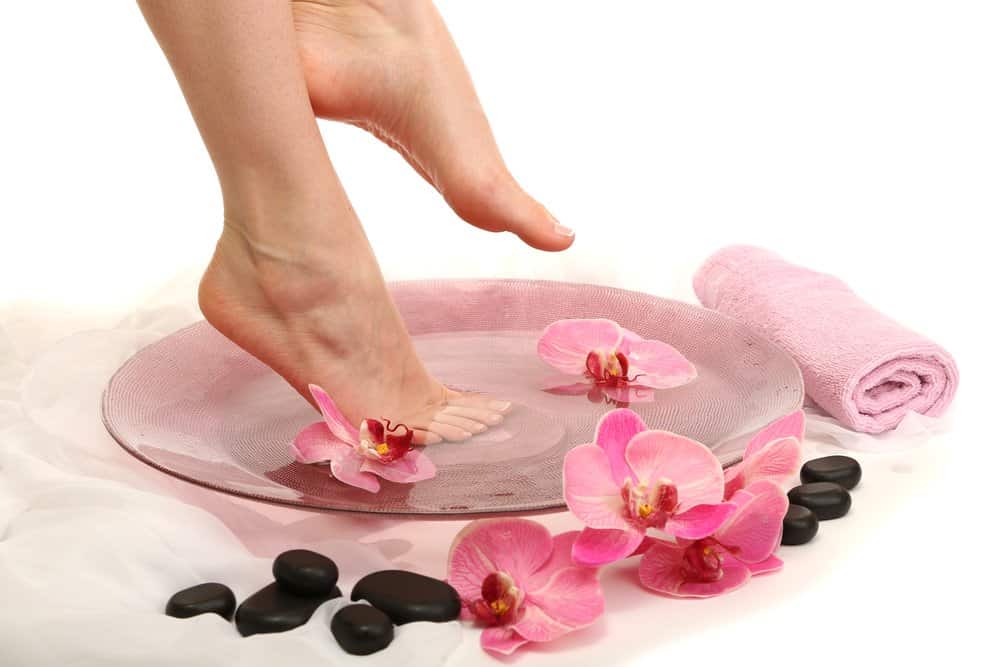 feet about to go into a bowl with water and flowers