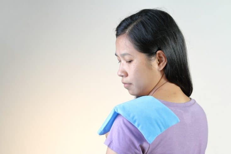 woman with a heat therapy pack on her shoulder