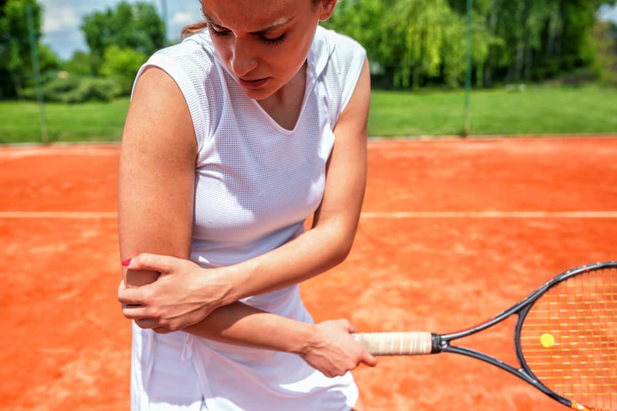 women tennis player holding her elbow in pain